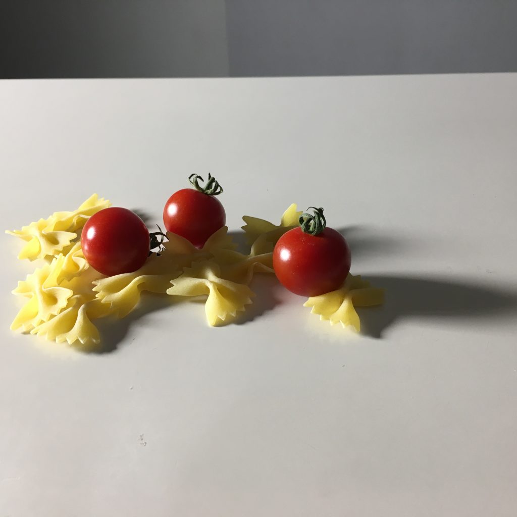 光を当てたパスタと3個のトマトの画像